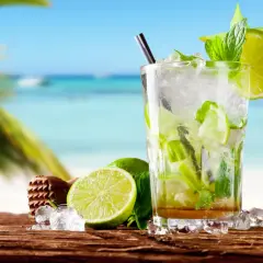Orzeźwiający mohito czy mojito na plaży? Szklanka pełna lodu, mięty i limonki, z widokiem na turkusowe morze.
