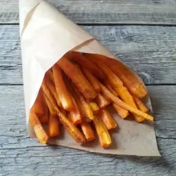 Chrupiące frytki z marchewki w papierowym rożku, gotowe do podania.