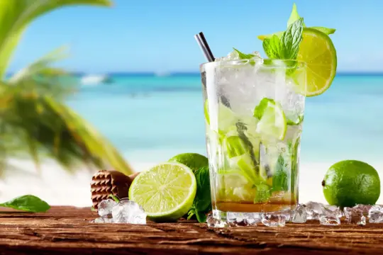 Orzeźwiający mohito czy mojito na plaży? Szklanka pełna lodu, mięty i limonki, z widokiem na turkusowe morze.