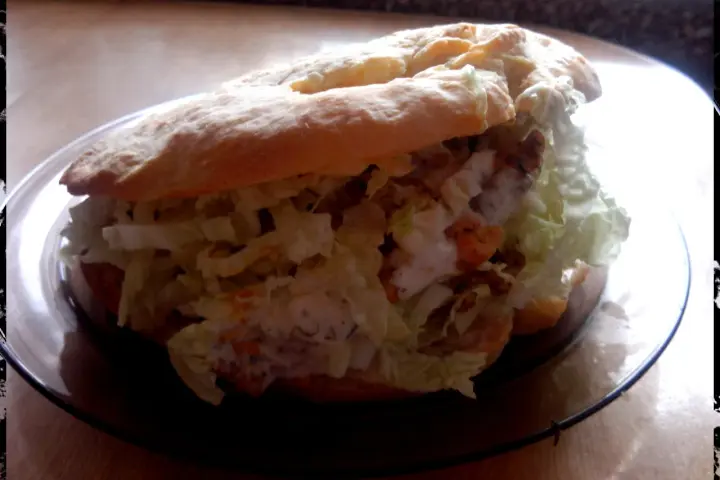 Pyszny kebab w bułce z chrupiącą sałatą i kremowym sosem, gotowy do zjedzenia.