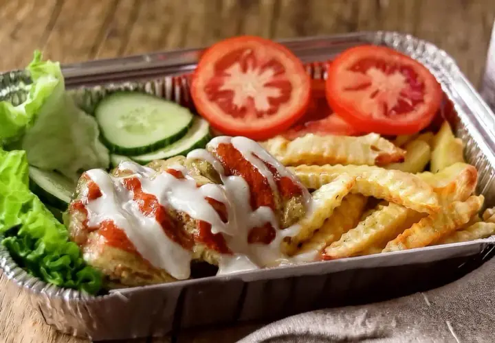 Pyszny kapsalon przepis z frytkami, mięsem, sałatą, pomidorem i ogórkiem, polany sosem.