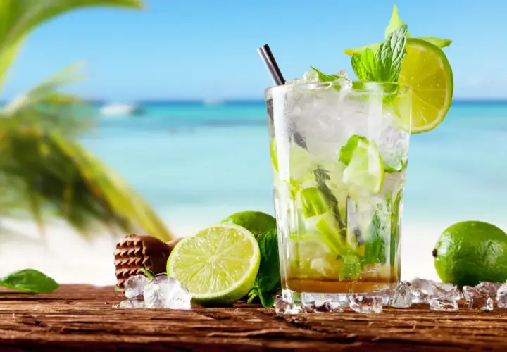 Orzeźwiający mohito czy mojito na plaży? Szklanka pełna lodu, mięty i limonki, z widokiem na turkusowe morze.
