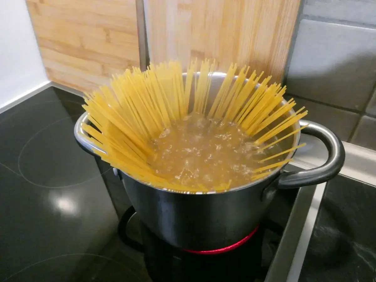 Długie, żółte nitki spaghetti gotują się w garnku z wrzącą wodą. Zastanawiasz się, ile gotować makaron spaghetti, by był idealny?